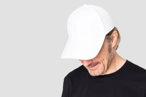 Homme en casquette de baseball blanche tirée vers le bas sur les yeux