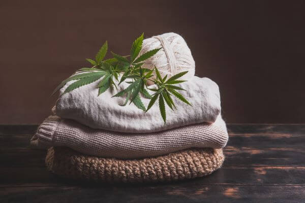 Clothing Material: Types Of Fabric And Their Uses 6 Hemp clothing in a pile with cannabis leaf on top