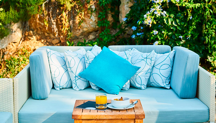 Terrasse avec canapé en osier et oreillers bleus