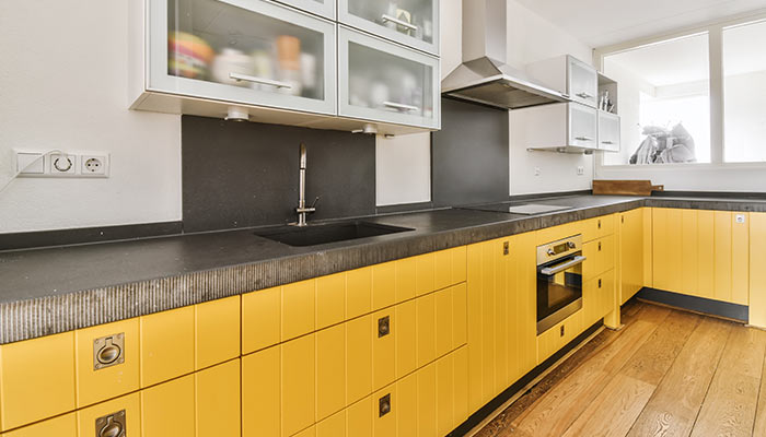 Une cuisine jaune avec un plan de travail gris
