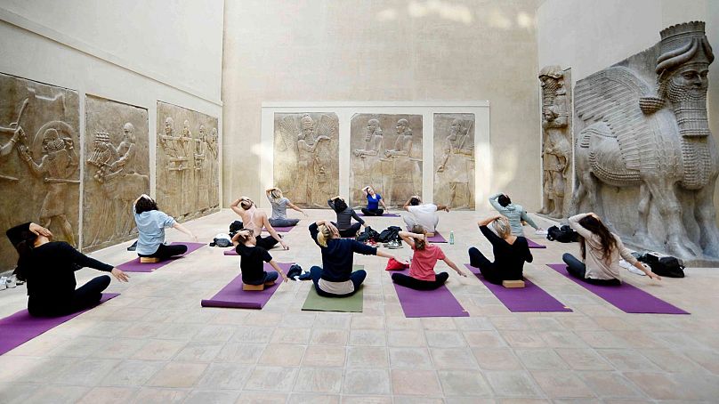 Le groupe pratique sur des tapis de yoga dans la cour Khorsabad du Louvre